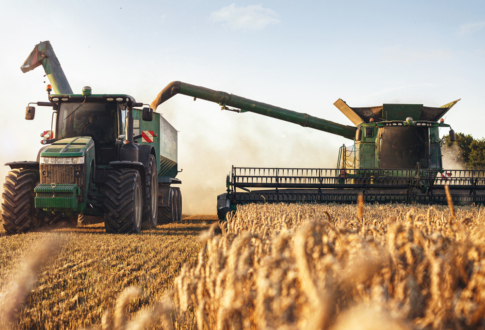 Harvester and tractor symbolizing MicroControl solutions for agricultural machinery